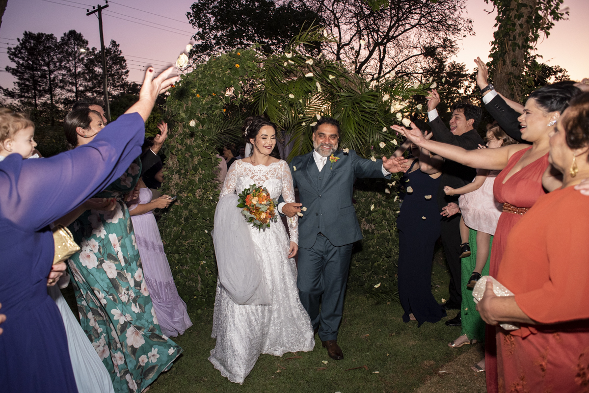 saida dos noivos no por do sol é registrada por fotografo de casamento em brotas após cerimonia religiosa no campo