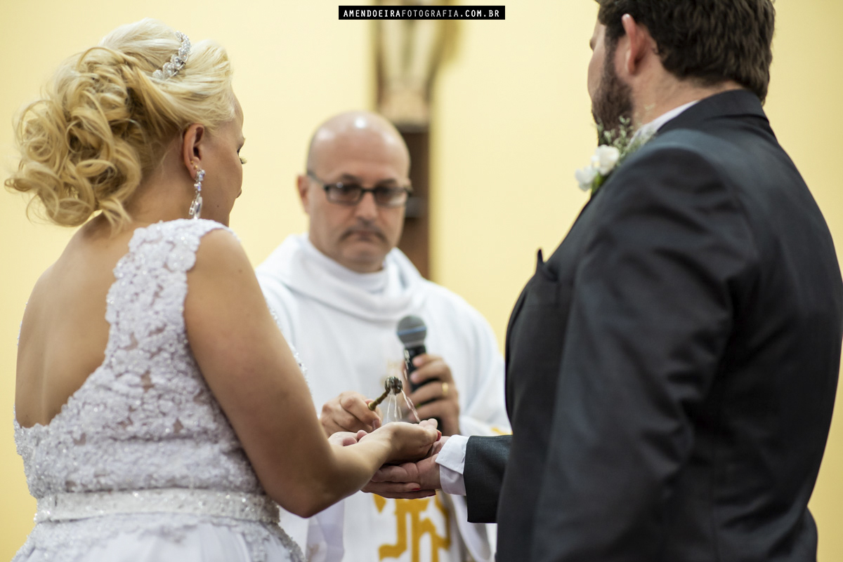 padre da paroquia sao benedito abencoa as aliancas dos noivos em cerimonia de casamento