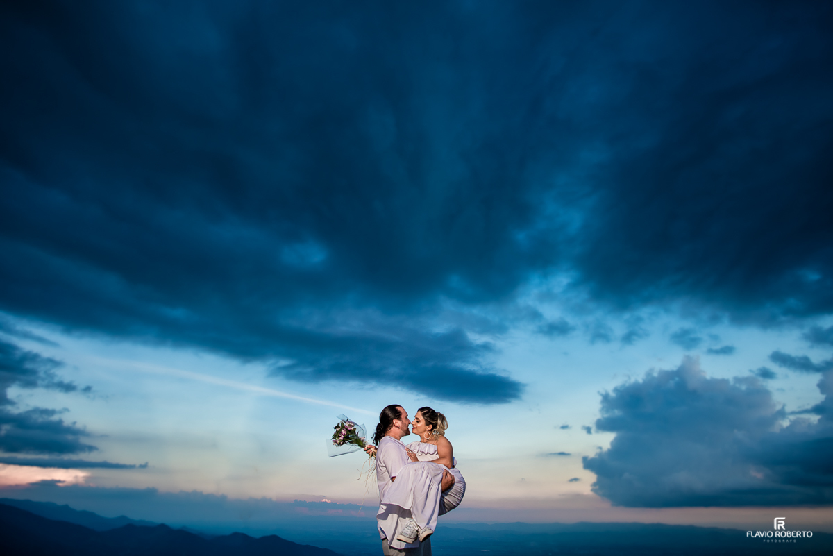 Noivo com sua noiva no colo no Pico Agudo de Santo Antônio do Pinhal durante entardecer