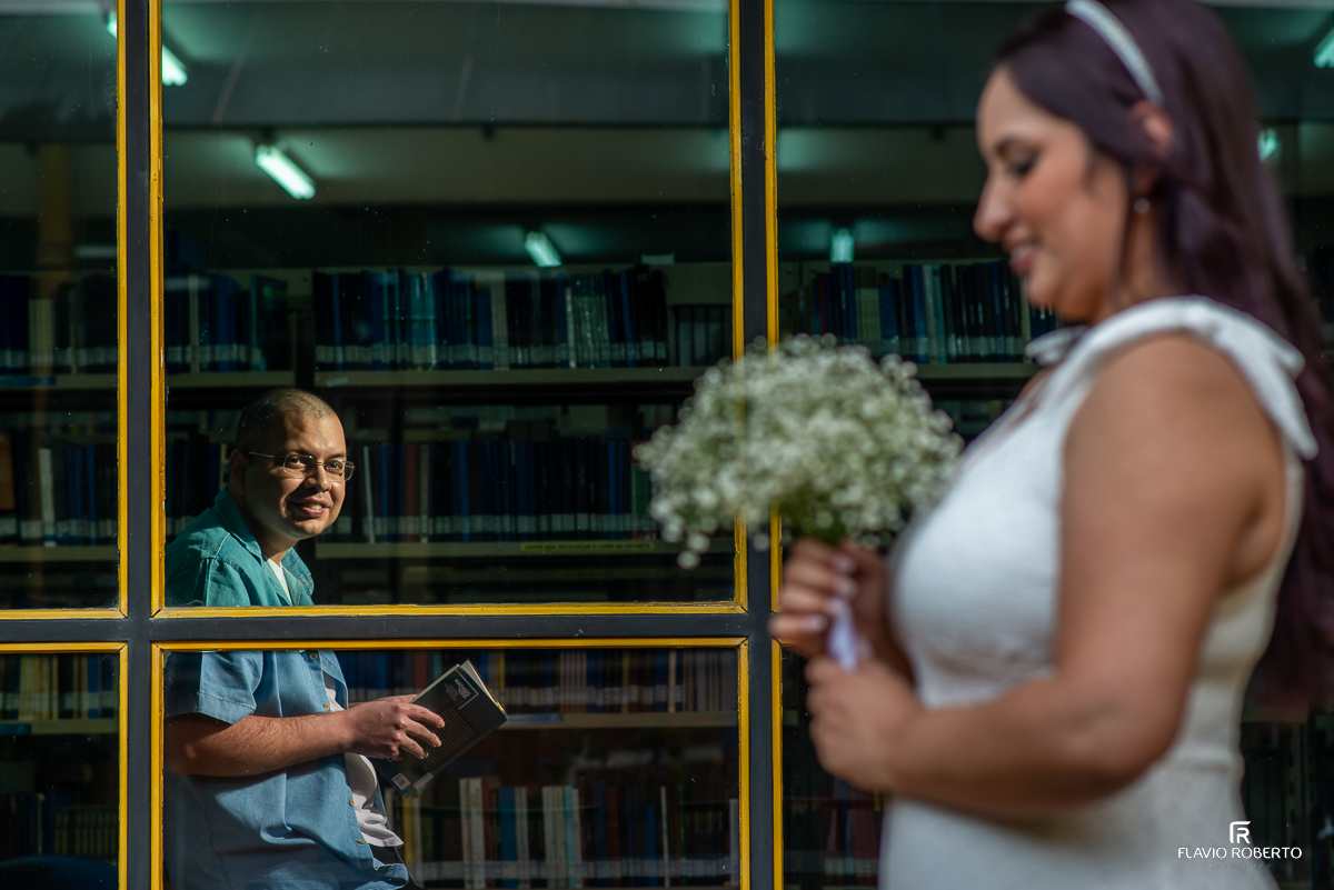 Noivo olhando sua noiva pela janela da Biblioteca da FEG em Guaratinguetá durante ensaio pre wedding na Unesp