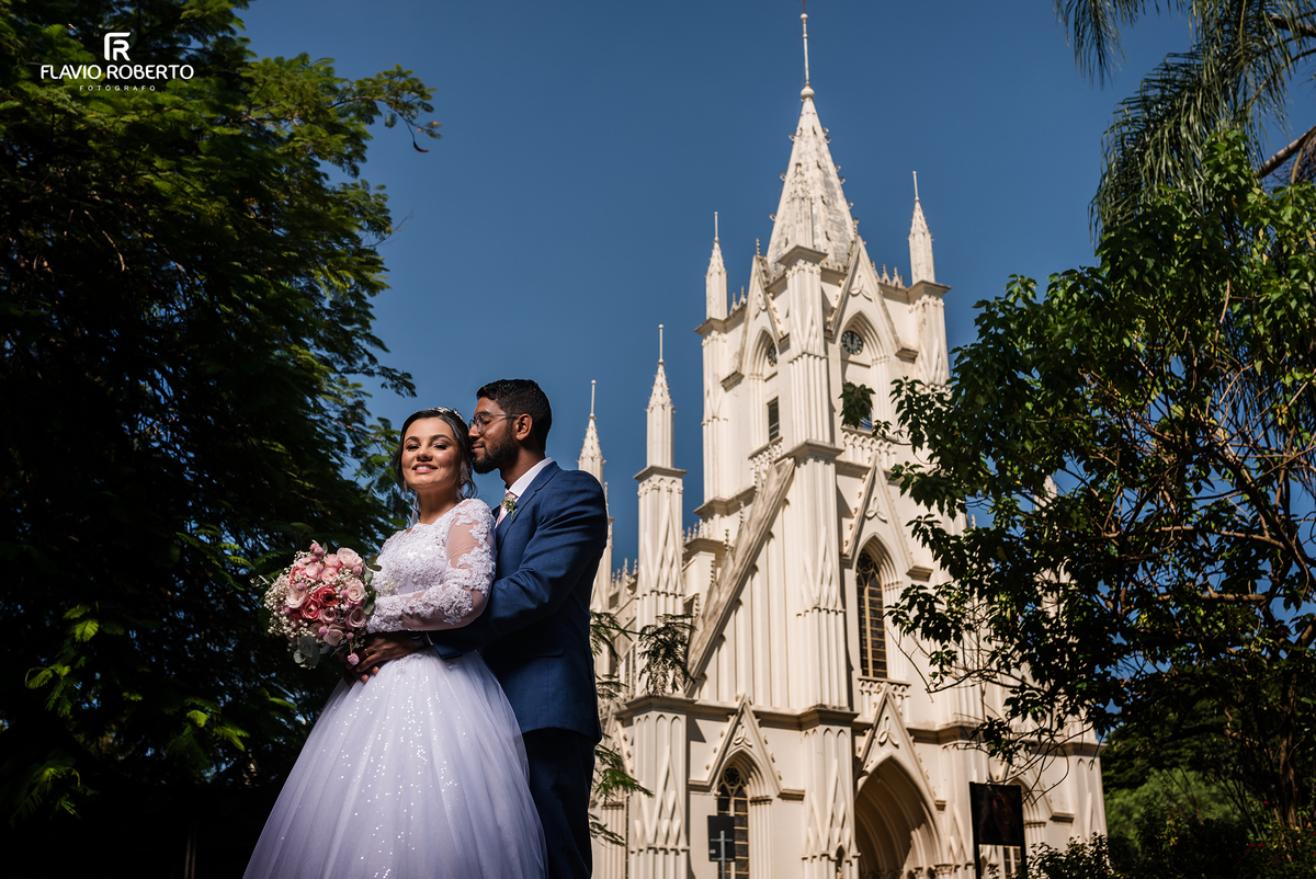 Noivos após casamento com Santuário Santa Teresinha ao fundo

