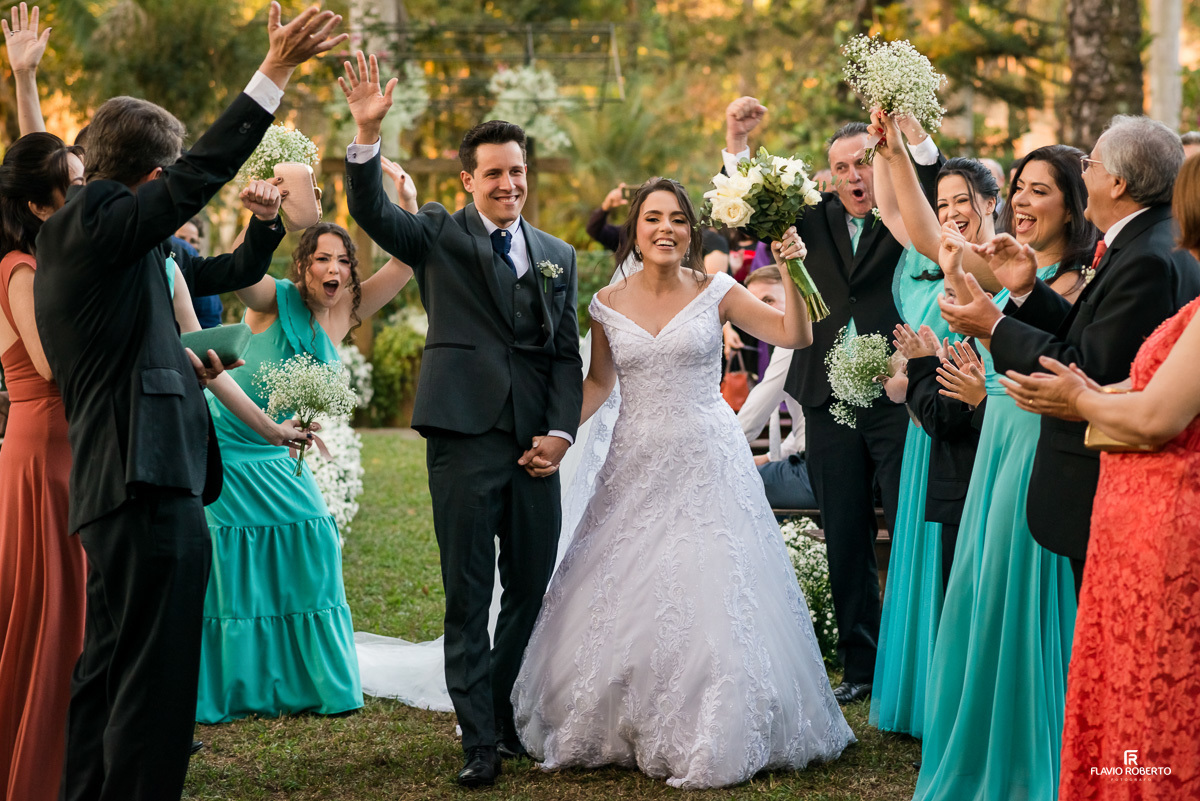 Casal saindo da cerimônia festejando entre os convidados durante Casamento no Espaço Verde Vale em Taubaté-SP