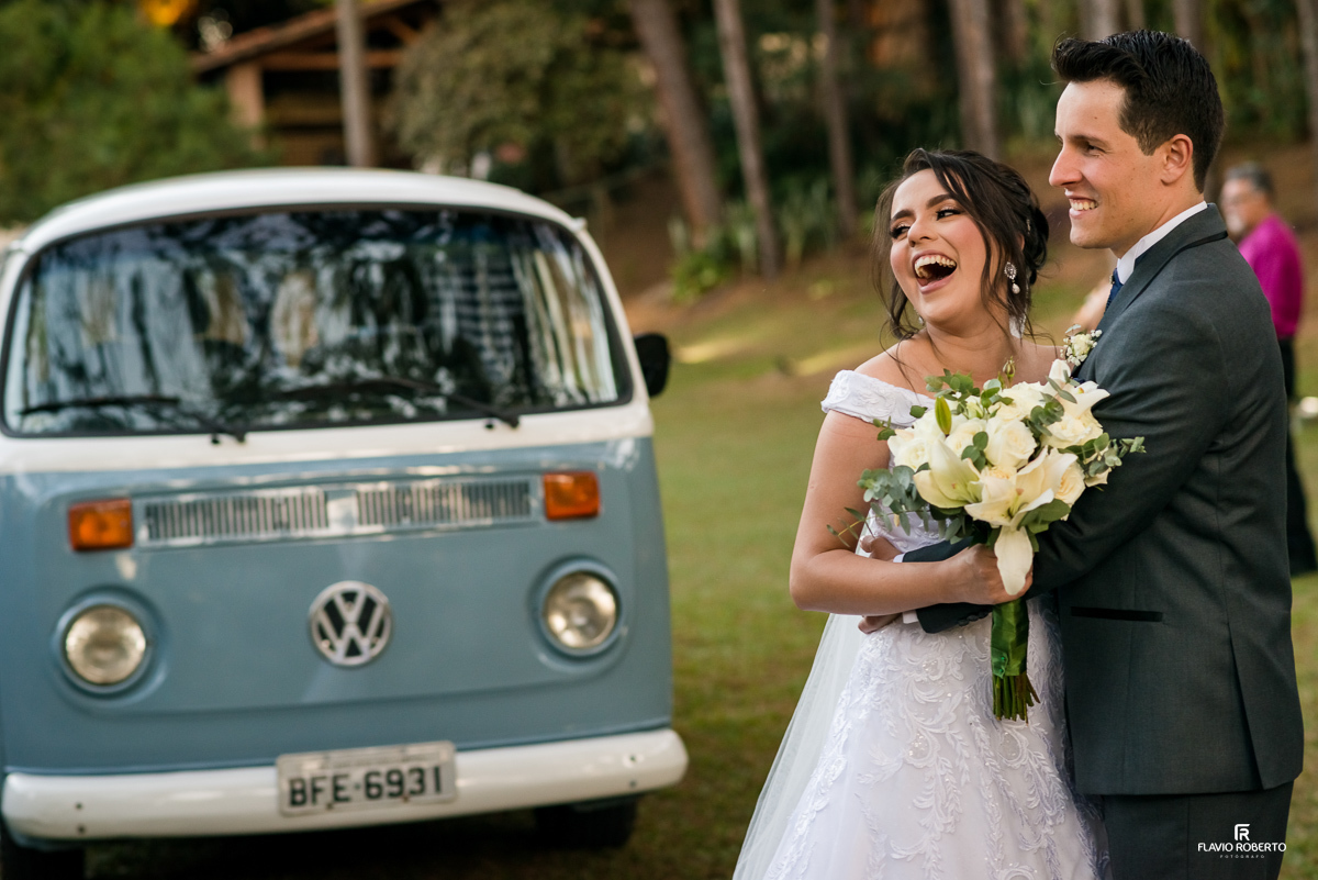 Noivos abraçados e rindo em frente a Kombi em Casamento realizado no Espaço Verde Vale em Taubaté-SP