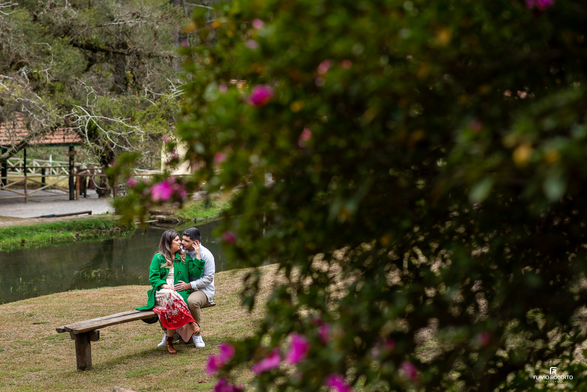 casal de namorados sentado em um banco no horto de campos de Jordão durante ensaio pre wedding