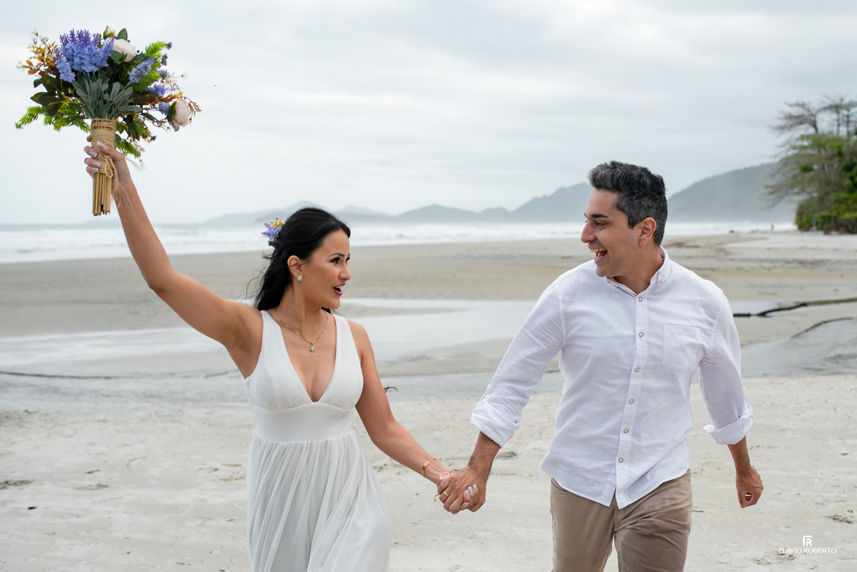 noivos correndo com o buquê durante Ensaio Pre Wedding na Praia Itamambuca de Ubatuba
