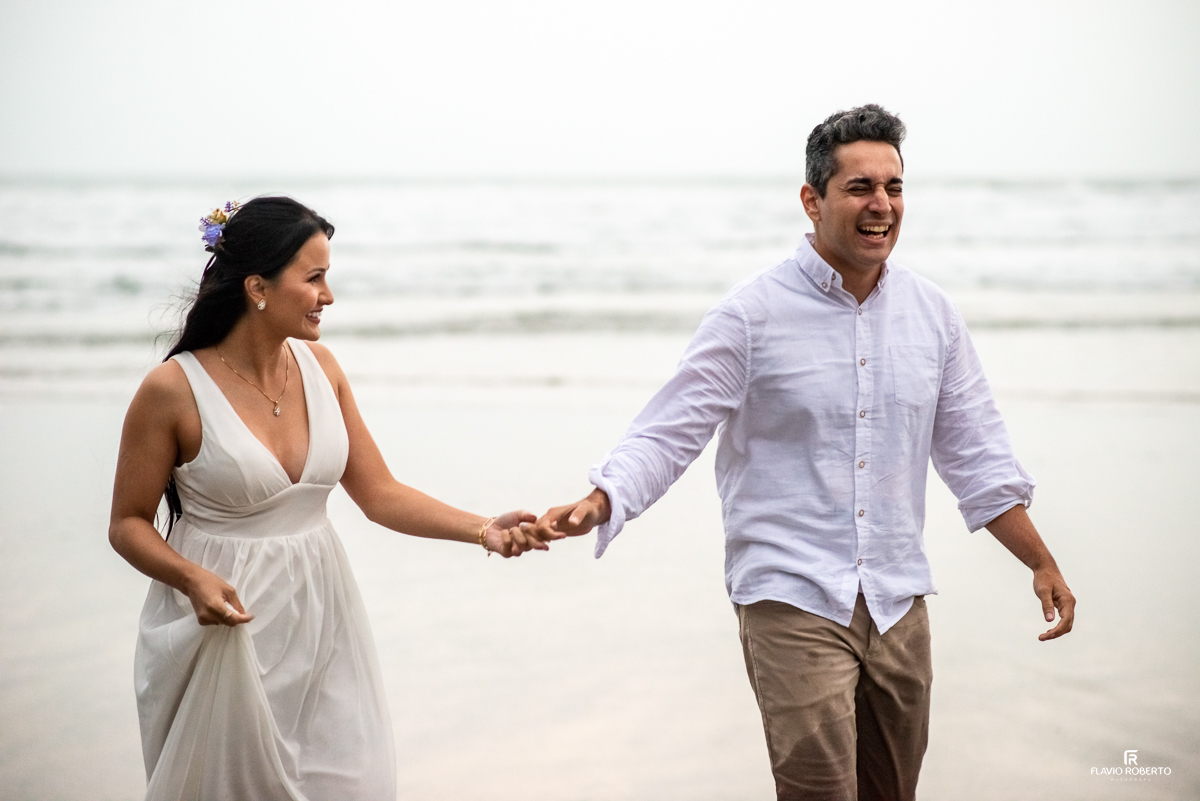 noivos de mãos dadas dando gargalhadas durante Ensaio Pre Wedding na Praia Itamambuca de Ubatuba