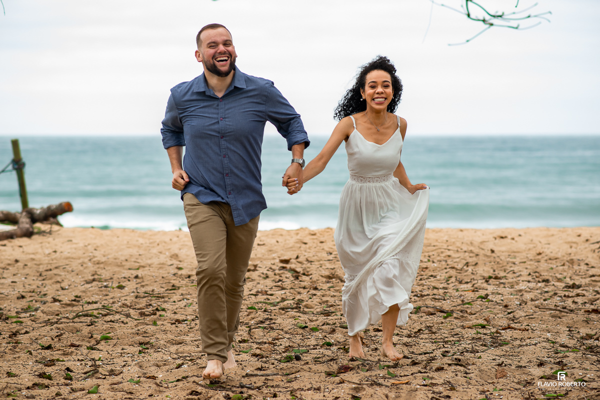 noivos correndo de mãos dadas na areia durante Ensaio Pre Wedding na praia vermelha do norte em ubatuba