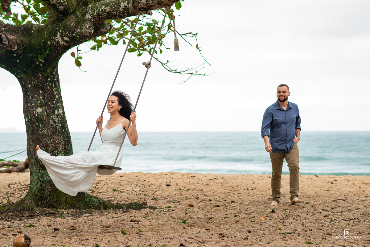 noiva no balanço sendo observada por seu noivo durante Ensaio Pre Wedding na praia vermelha do norte em ubatuba