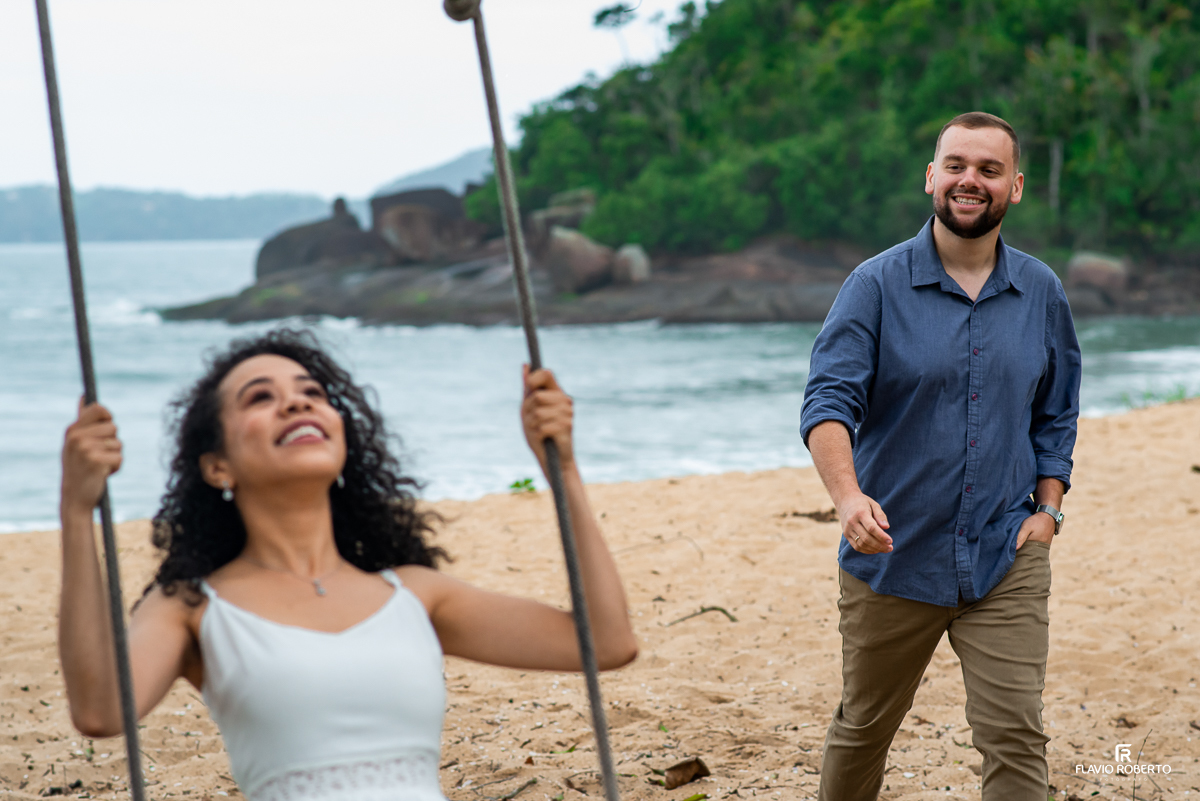 noiva no balanço sendo observada por seu noivo durante Ensaio Pre Wedding na praia vermelha do norte em ubatuba