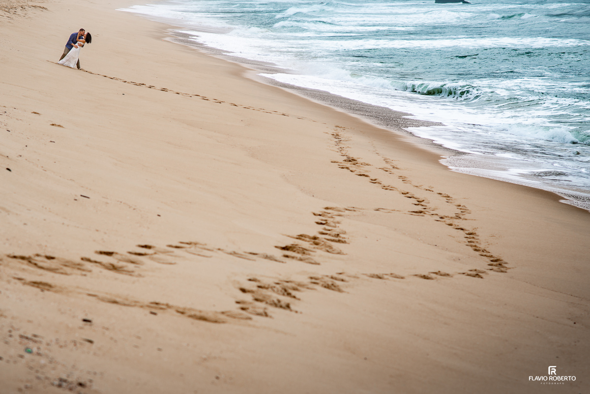 pegadas do casal na areia com eles se beijando durante Ensaio Pre Wedding na praia vermelha do norte em ubatuba
