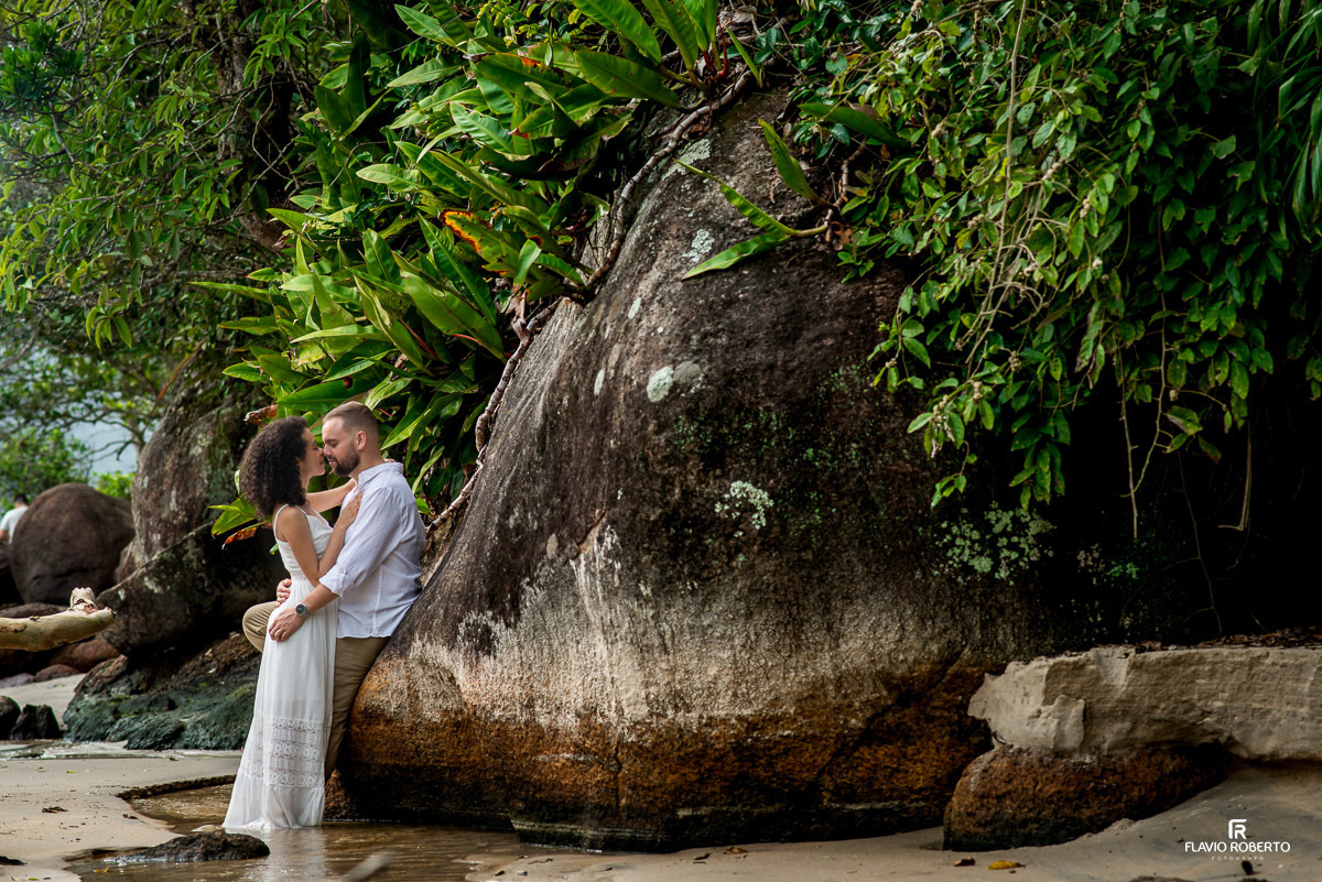 casal abraçado encostado nas rochas durante Ensaio Pre Wedding na praia vermelha do norte em ubatuba