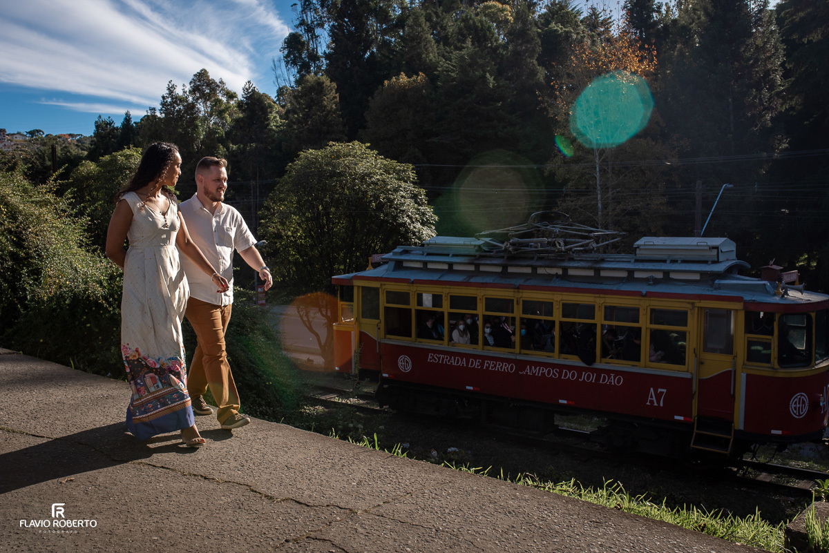 casal caminhando pala calçada olhando o trem passar durante Ensaio Pre Wedding em Campos do Jordão