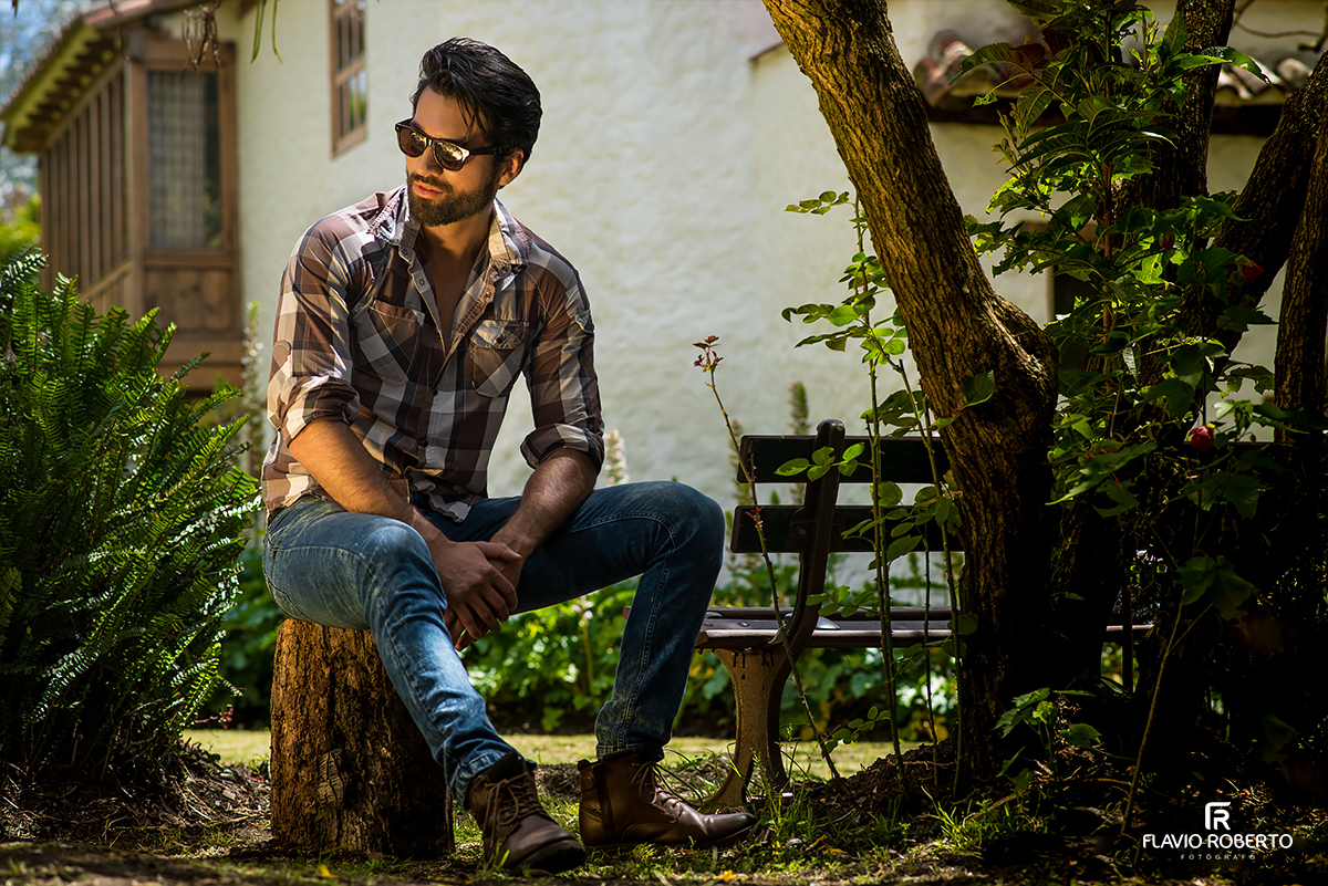 modelo sentado em um tronco de madeira no ensaio fotografico