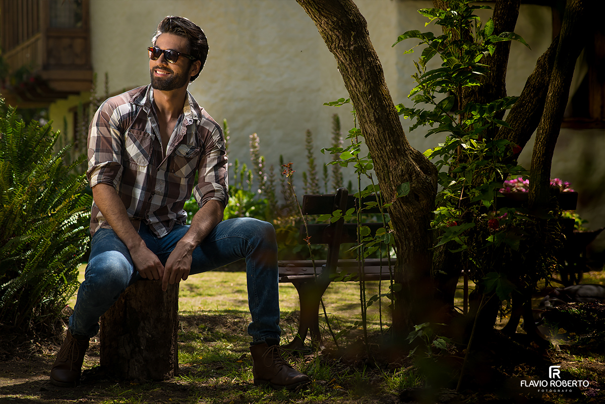 modelo sentado em um tronco de madeira no ensaio fotografico