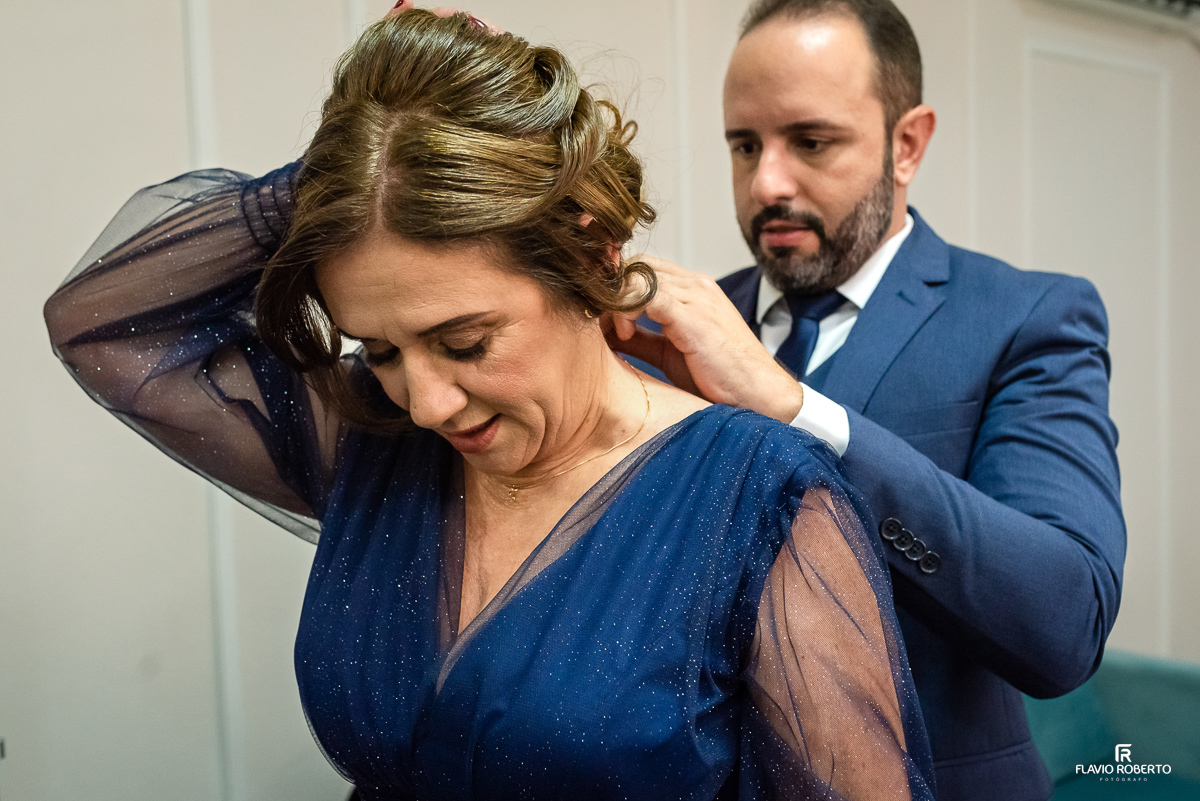 Noivo colocando o colar em sua mãe durante o making of no Espaço Luxo em Taubaté