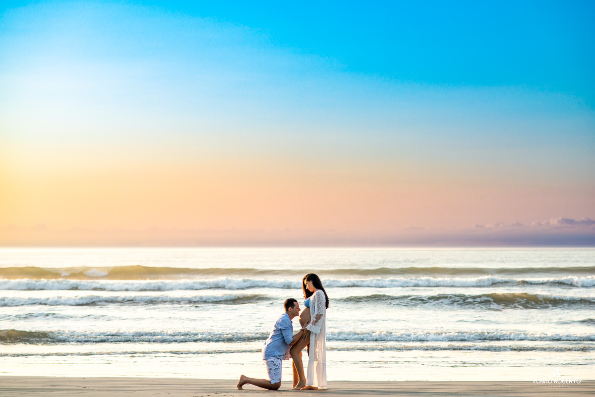 Pai ajoelhado beijando a barriga da mãe durante o nascer do sol na praia Itamambuca em Ubatuba