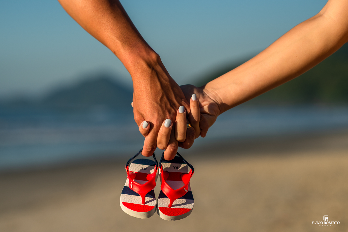 sapatinho do bebê sendo segurando pelos pais durante ensaio de gestante na praia de Itamambuca em Ubatuba