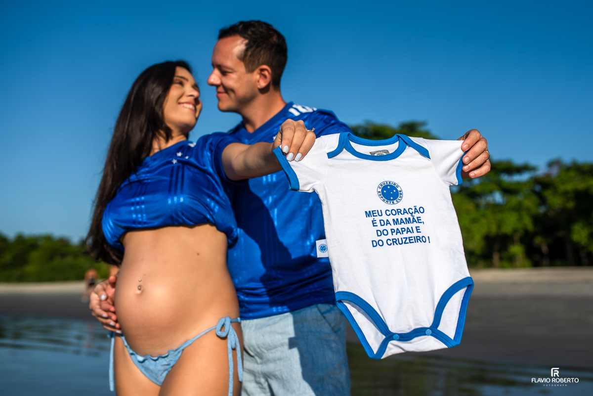 casal gestante segurando a camiseta do Cruzeiro durante ensaio de gestante na praia de Itamambuca em Ubatuba