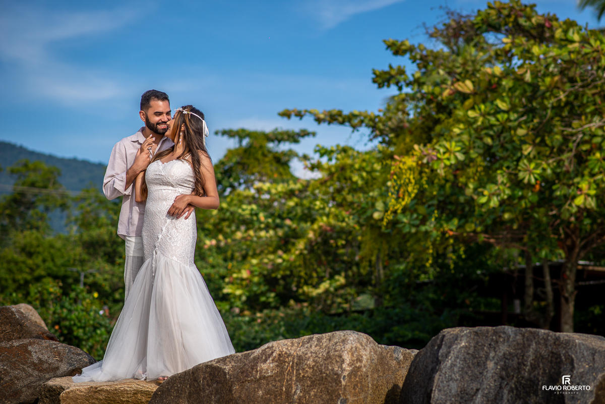 casal vestido de noivos abraçados sobre rochas, durante ensaio pre wedding em Ilhabela