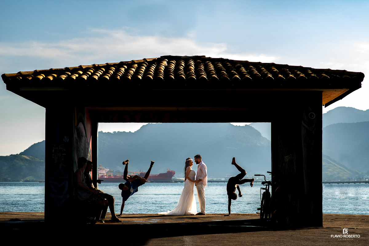 casal abraçado em um pier no meio de dois capoeiristas, durante ensaio pre wedding em Ilhabela