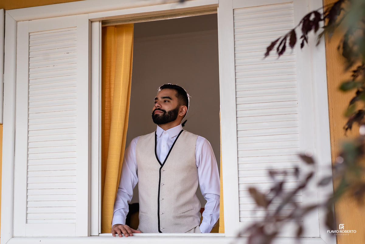 Noivo olhando pela janela antes de iniciar Casamento no Rancho Mustang em Pindamonhangaba.