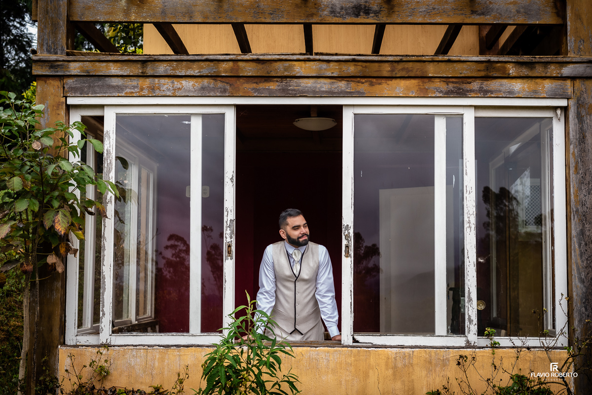 Noivo arrumado olhando pela janela no Casamento no Rancho Mustang em Pindamonhangaba.