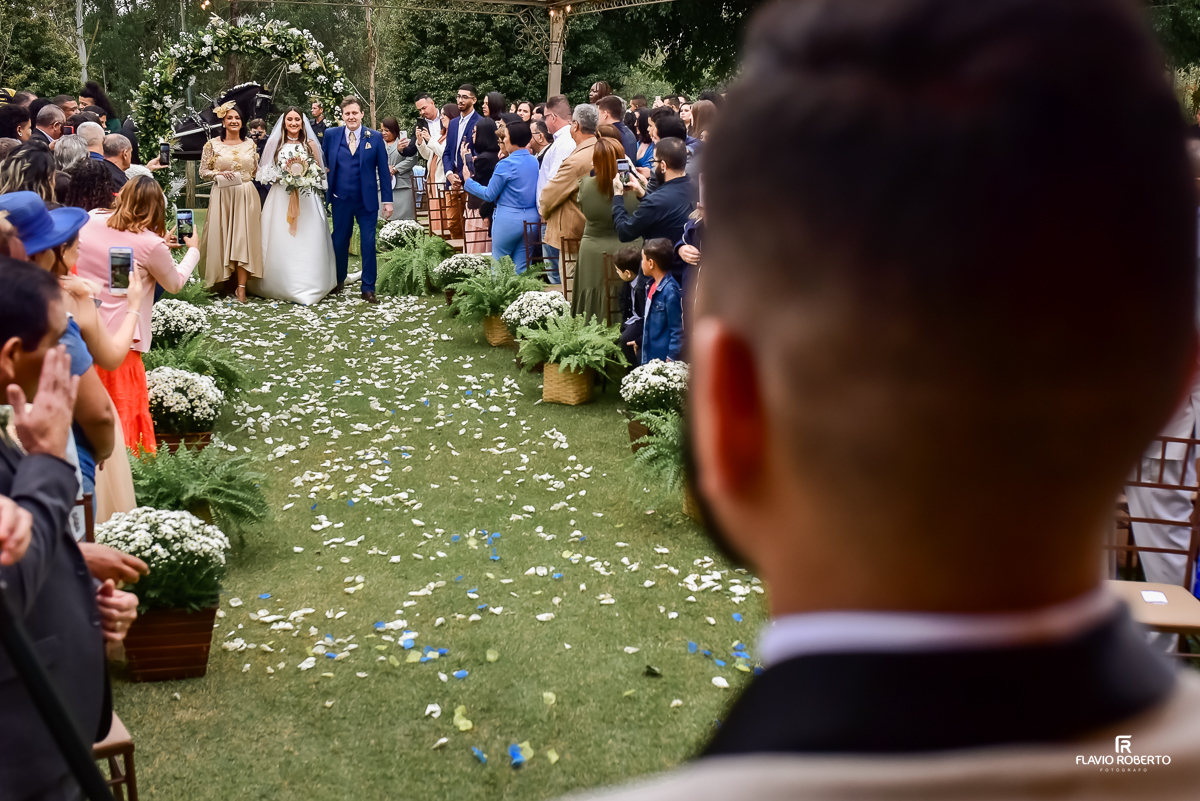 Noivo olhando a noiva entrar acompanhada de seus pais durante Casamento no Rancho Mustang em Pindamonhangaba.