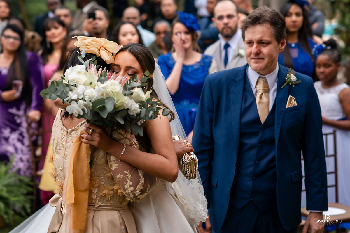 noiva abraçando sua mae, sendo observada por seu pai, durante Casamento no Rancho Mustang em Pindamonhangaba.