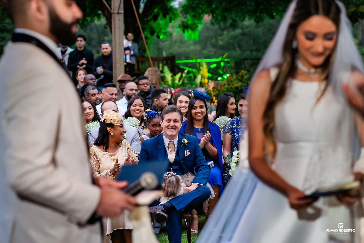 Pais da noiva rindo durante votos dos noivos durante Casamento no Rancho Mustang em Pindamonhangaba.