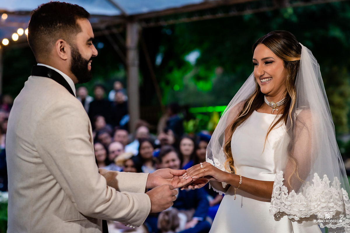 Noivos colocando a aliança sorrindo durante Casamento no Rancho Mustang em Pindamonhangaba.
