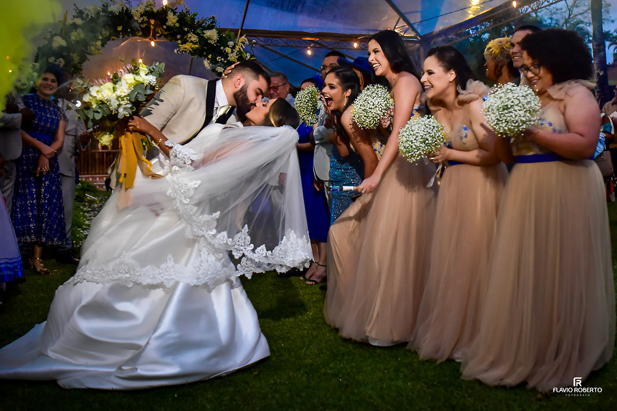  Noivo beijando sua esposa na saída da cerimônia, sendo aplaudidos pelas damas de honra no Casamento no Rancho Mustang em Pindamonhangaba.
