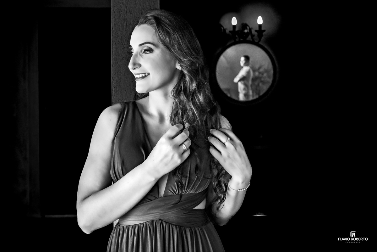 noiva arrumando o cabelo, sendo observada pelo seu noivo olhando pelo espelho