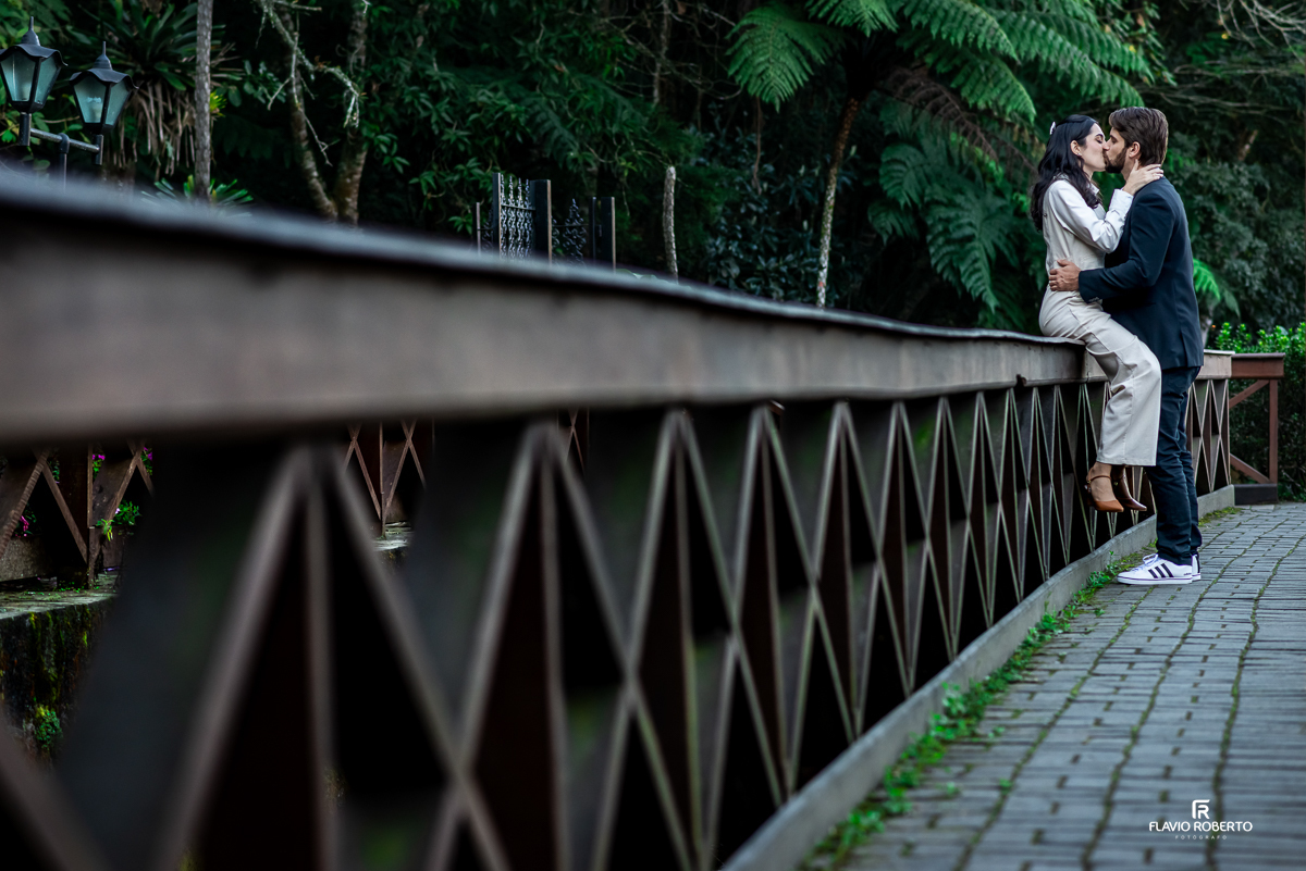 Momento romântico de Laís e Gabriel se beijando próximos à famosa Fonte Santo Antônio, em meio à natureza da cidade.