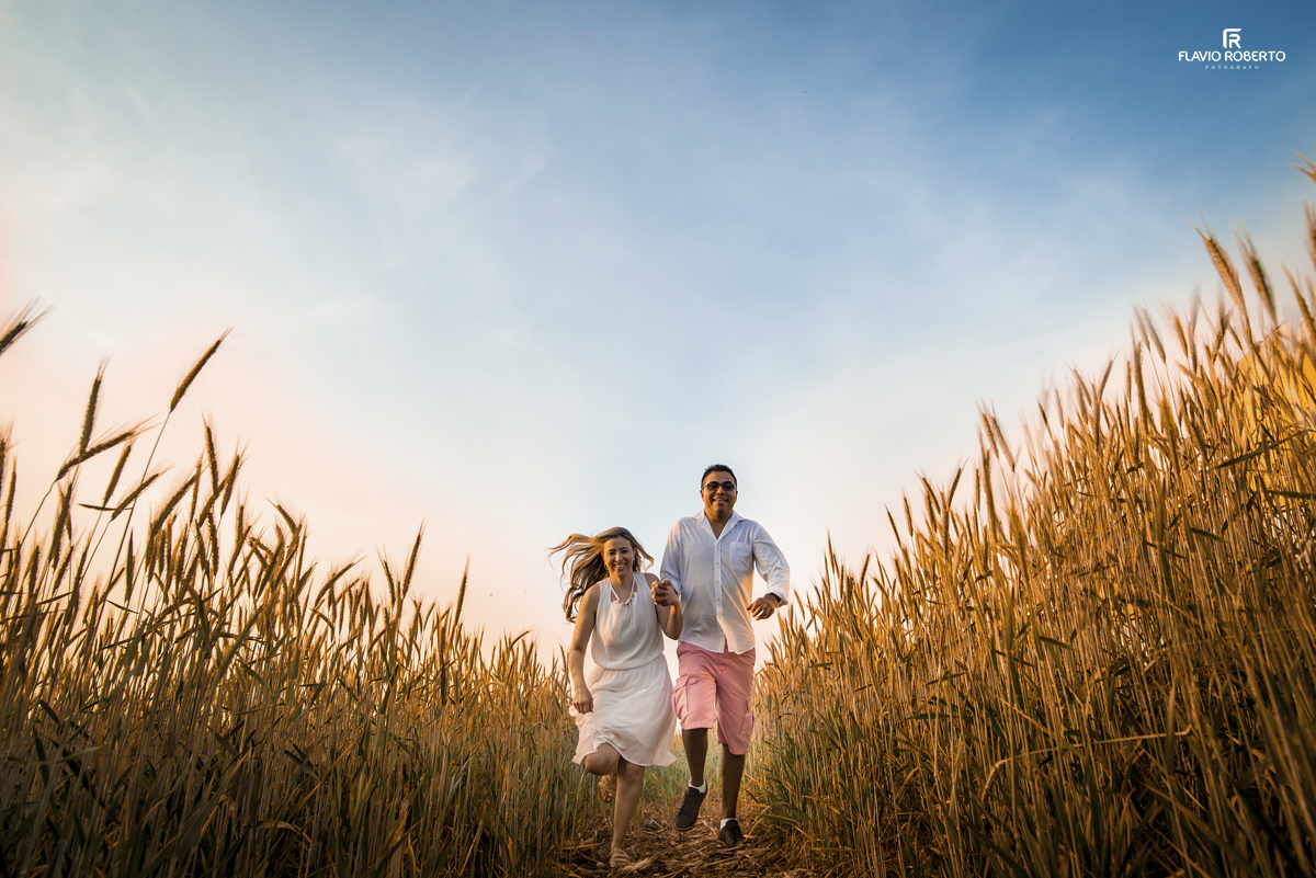 namorados correndo na plantação de trigo durante Ensaio Pre Wedding em Holambra