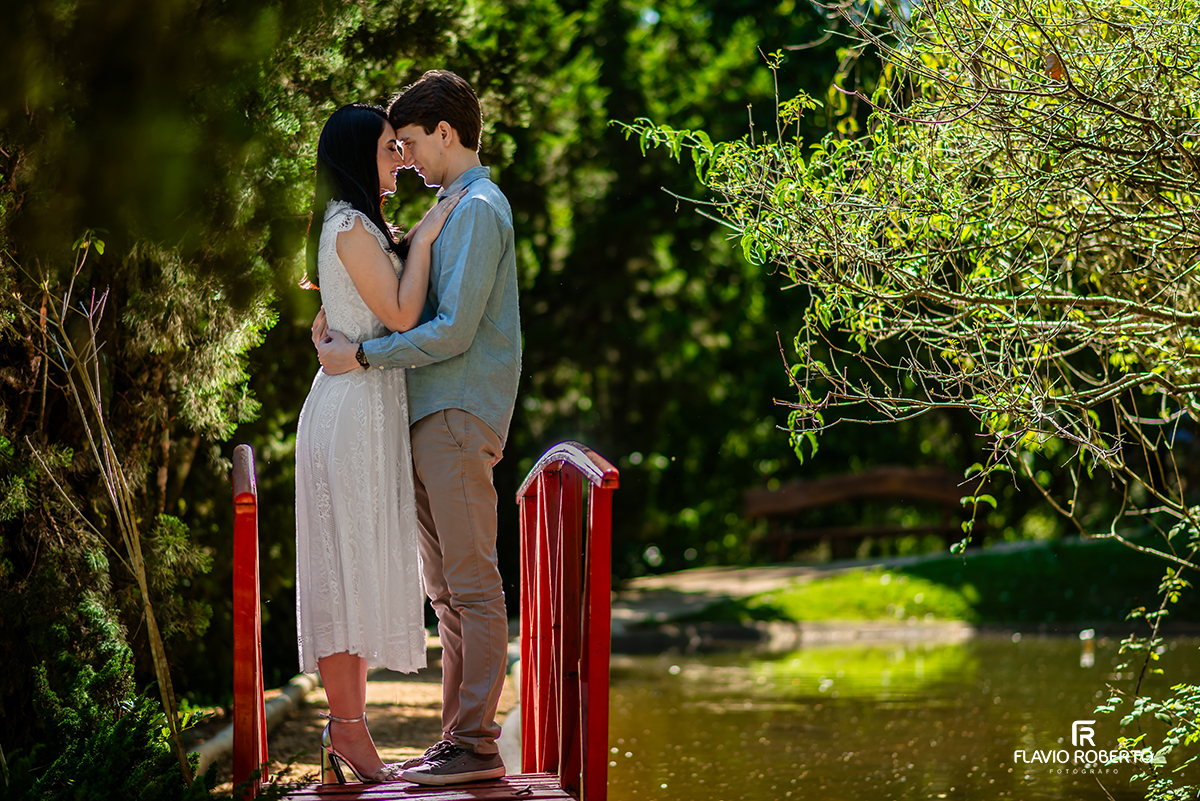 Casal em ensaio pré casamento no Jardim dos Pinhais em SP, sobre ponte vermelha em meio ao jardim.