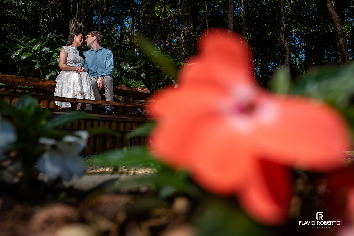 Casal sentado em banco de madeira durante ensaio pré casamento no Jardim dos Pinhais, Serra da Mantiqueira.