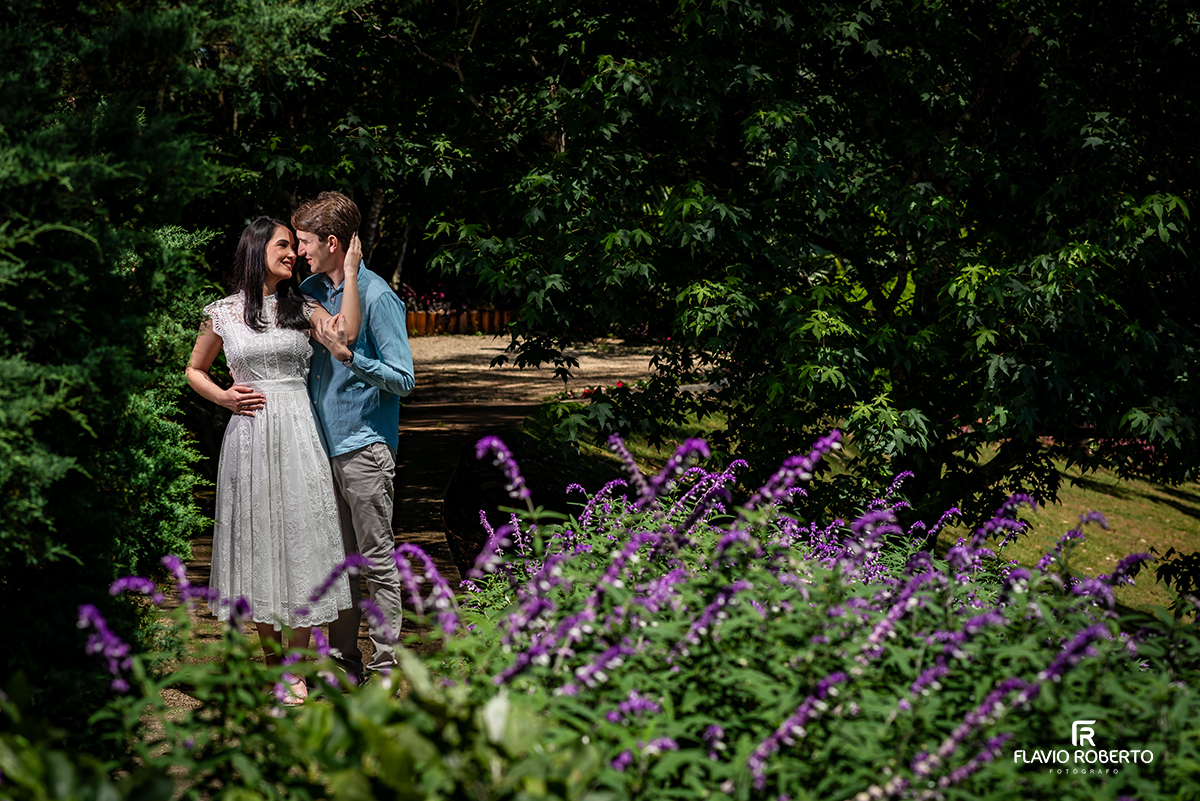 Casal abraçado entre flores roxas em ensaio pré casamento no Jardim dos Pinhais, interior de São Paulo.