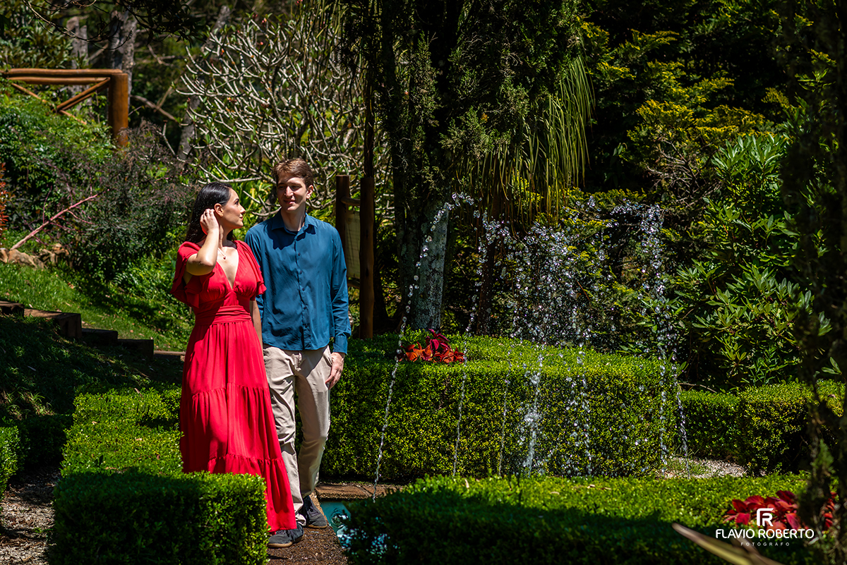 Casal caminhando entre jardins e fontes no ensaio pré casamento no Jardim dos Pinhais, Campos do Jordão.