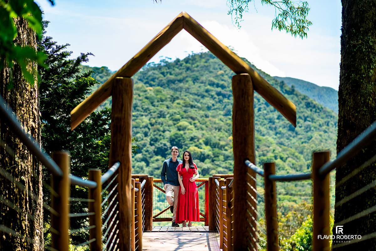 Ensaio pré casamento no Jardim dos Pinhais em SP, casal posando na ponte com vista para as montanhas.
