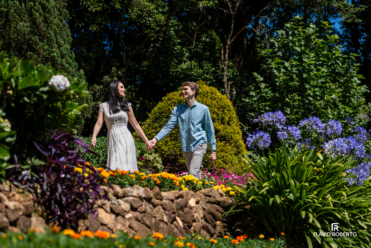 Ensaio pré casamento no Jardim dos Pinhais em SP, casal de mãos dadas entre flores coloridas no jardim.