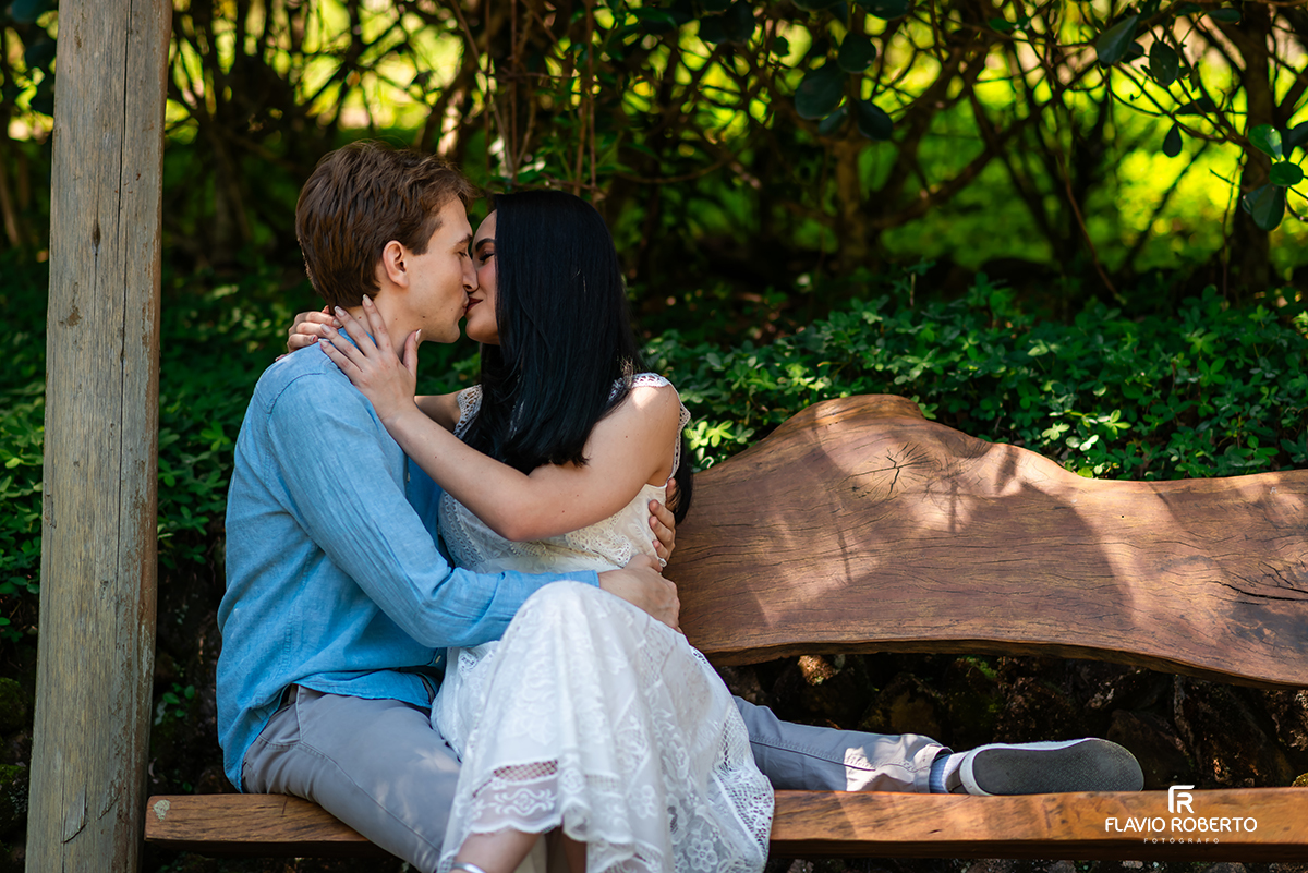 Casal se beijando em banco rústico durante ensaio pré casamento no Jardim dos Pinhais em SP.