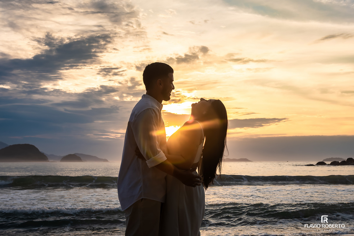 Silhueta de casal em ensaio pré casamento na Praia de Ubatuba durante o nascer do sol, fotografia artística e cheia de emoção
