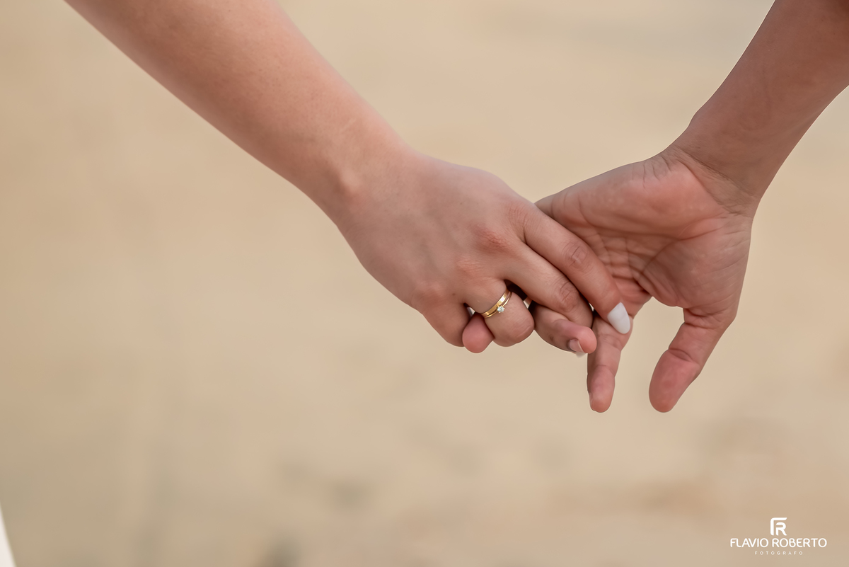 Detalhe das mãos com aliança em ensaio pré casamento na Praia de Ubatuba, conexão real e amor verdadeiro