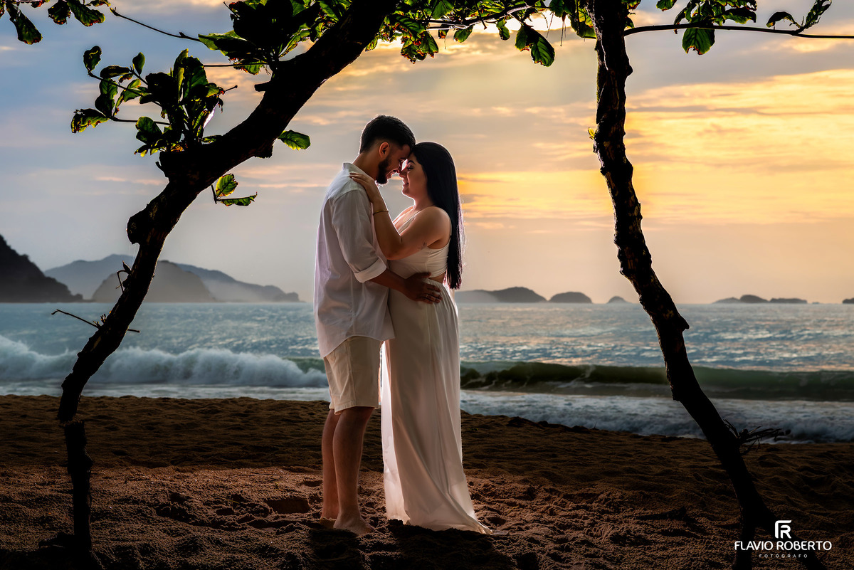 Ensaio pré casamento na Praia de Ubatuba com casal abraçado durante o nascer do sol, emoção verdadeira e fotografia autoral