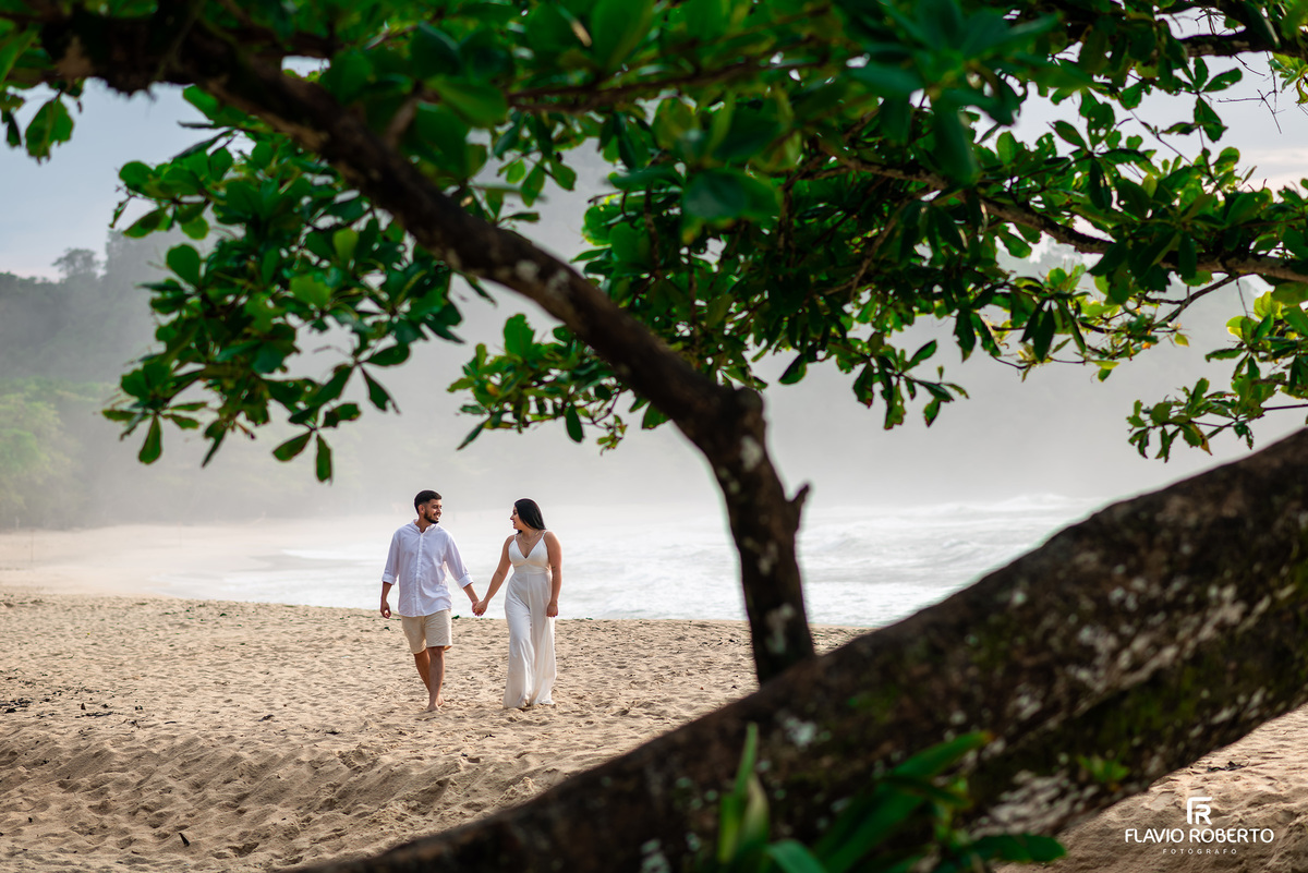 Ensaio pré casamento na Praia de Ubatuba ao amanhecer com casal caminhando na areia, composição artística e natural