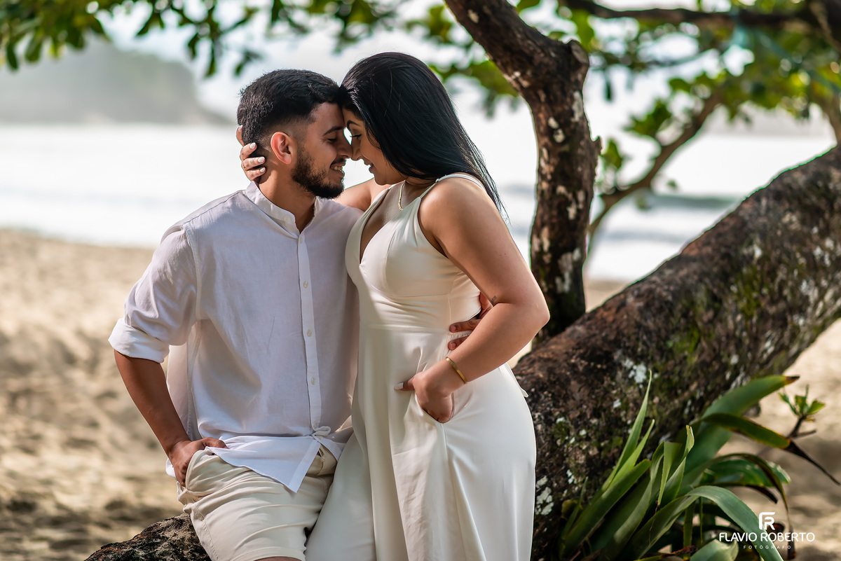 Ensaio pré casamento na praia de Ubatuba ao nascer do sol com casal junto à árvore, fotos românticas e naturais