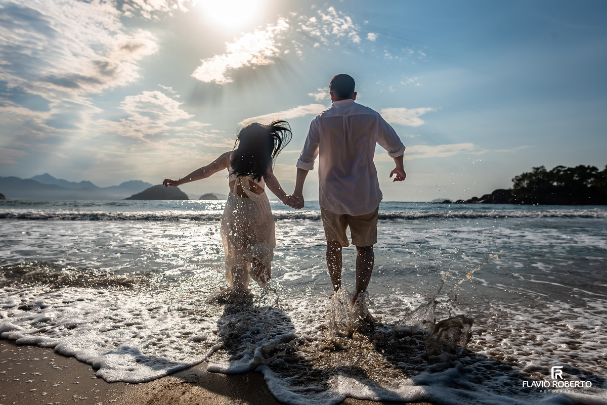 Ensaio pré casamento na Praia de Ubatuba ao amanhecer com casal entrando no mar, luz natural e emoção verdadeira