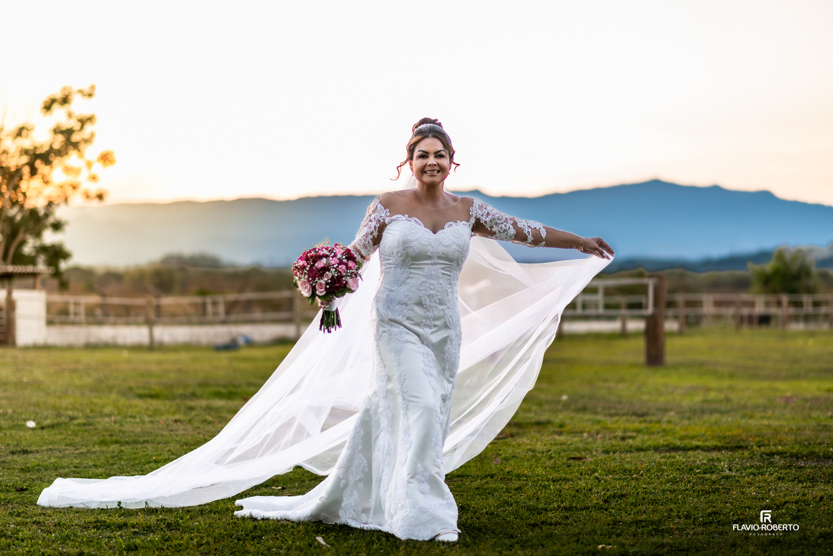 Noiva com buquê e véu esvoaçante durante ensaio na Hípica Cachoeira Paulista