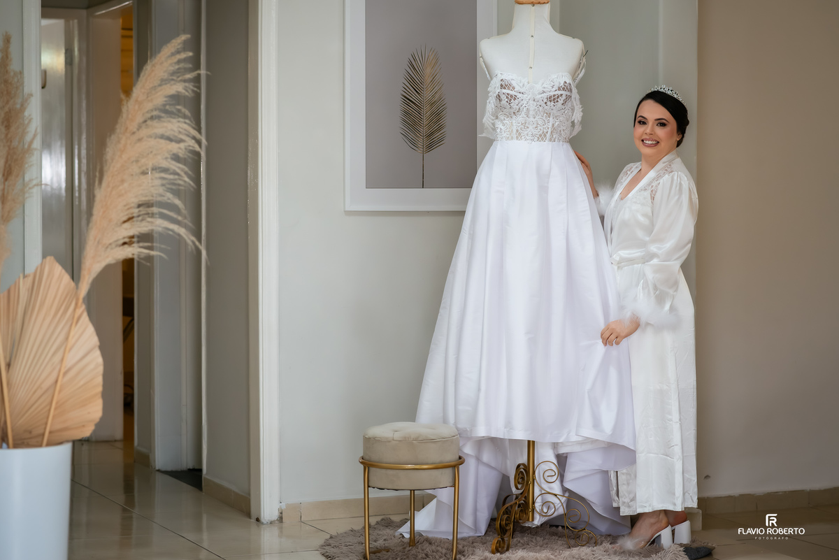 Noiva com robe ao lado do vestido de casamento durante o making of no Studio da Graziele Resende em Guaratinguetá