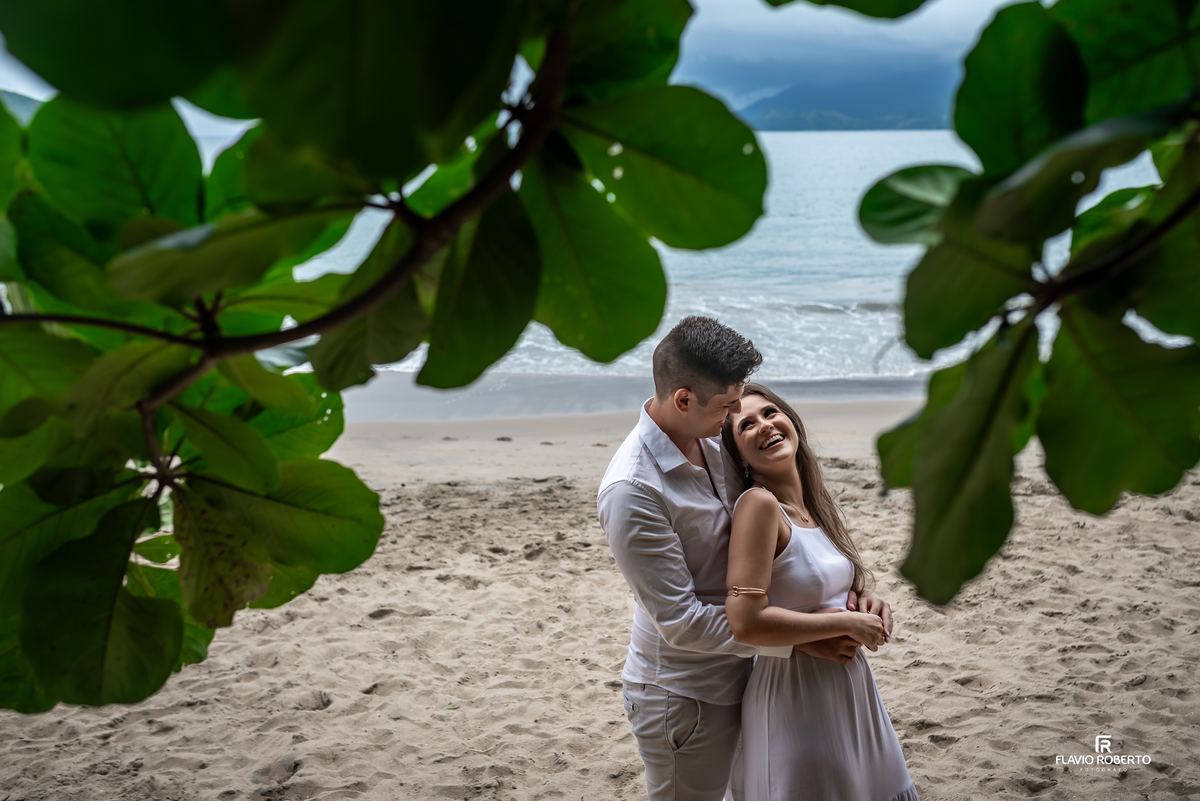 Ensaio pré casamento na Praia da Almada em Ubatuba com moldura natural de folhas, conexão verdadeira e fotos emocionais
